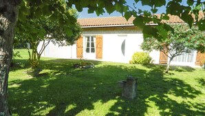 A house with a tiled roof, a grassy yard, and a tree in the foreground. - Homerez - House Le Verdon + Private Garden (Le Verdon-sur-Mer)