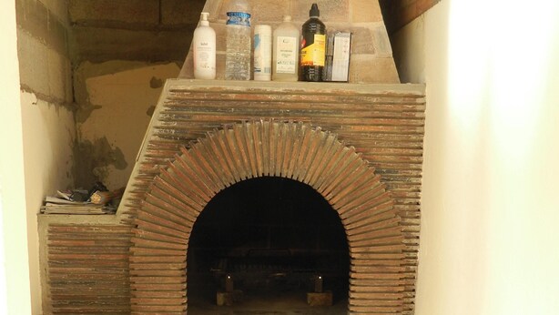 A brick oven with a shelf above it holding cleaning supplies. - Homerez - House Le Verdon + Private Garden (Le Verdon-sur-Mer)