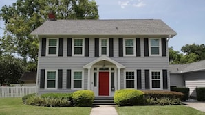 A two-story house with a red front door, white trim, and a small porch. - 8th Green Cottage "A relaxing Oasis in the city" Guesthouse (Orlando)