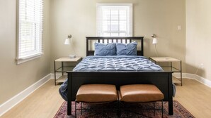 A bedroom with a bed, two nightstands, a window, and a rug. - 8th Green Cottage "A relaxing Oasis in the city" Guesthouse (Orlando)