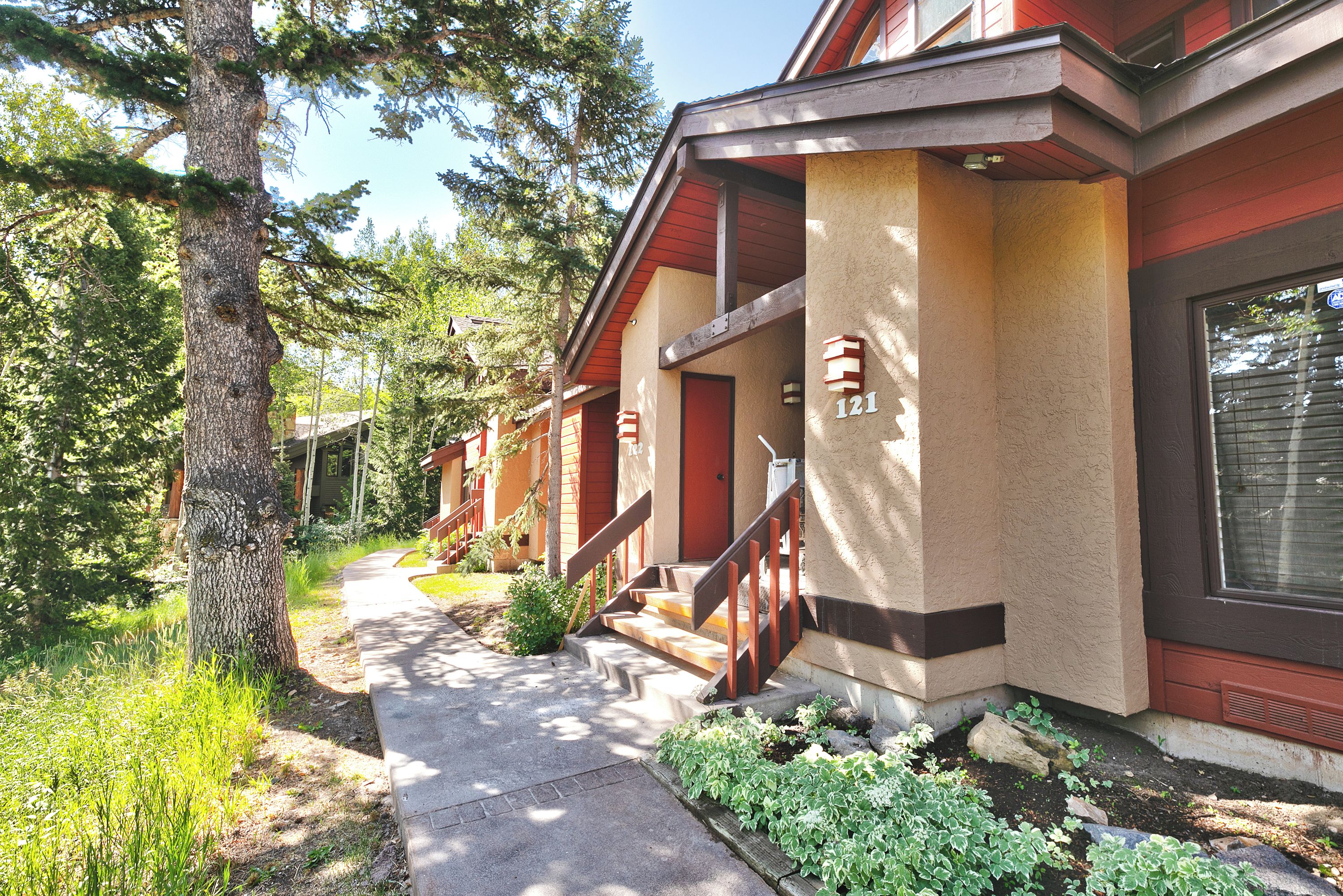 A residential building with a covered porch, a visible staircase, and a pathway leading to the entrance.
