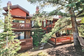 A multi-story building with balconies, surrounded by trees.