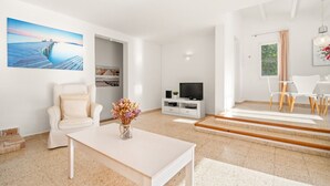 A modern living room with a white sofa, a coffee table, a TV, and a painting of a pier.