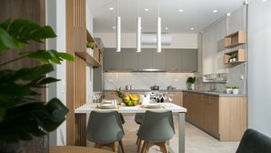 A modern kitchen with wooden cabinets, a marble countertop, and pendant lighting.