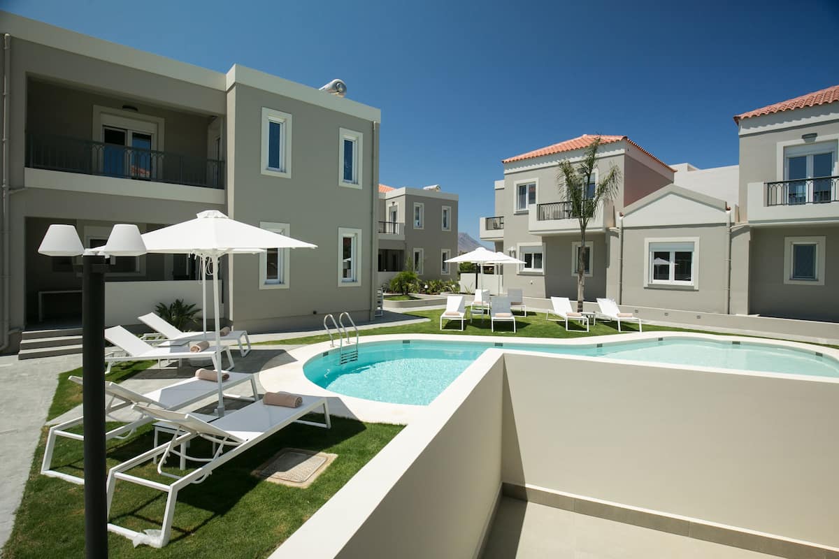 Un hotel moderno con piscina, tumbonas y sombrillas.