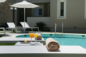 Una piscina al aire libre, sombrillas, sillones reclinables de piscina
