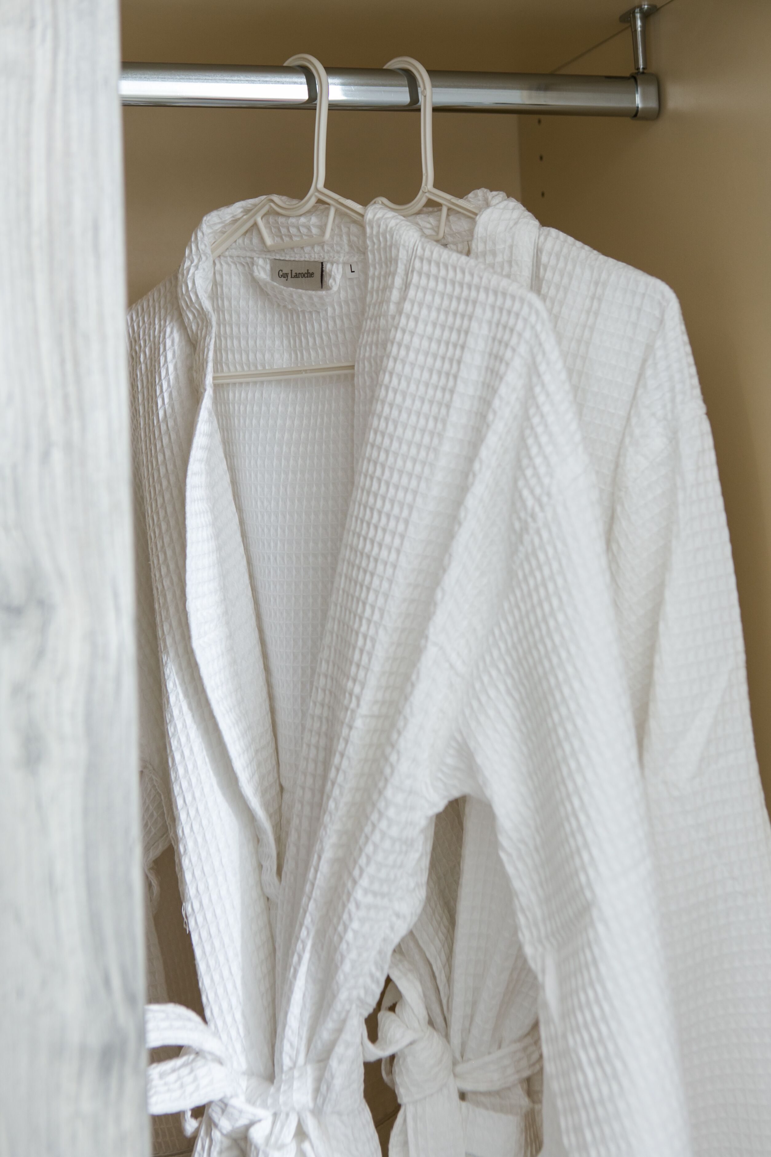 A white robe hanging on a metal rack in a bathroom.