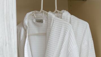 A white robe hanging on a metal rack in a bathroom.