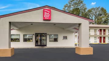 Un Red Roof Inn à l’apparence simple, avec une entrée abritée et un parking situé à l’avant.