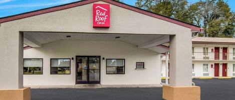Ett Red Roof Inn med en enkel fasad, en överbyggd entré och en parkeringsplats framför.