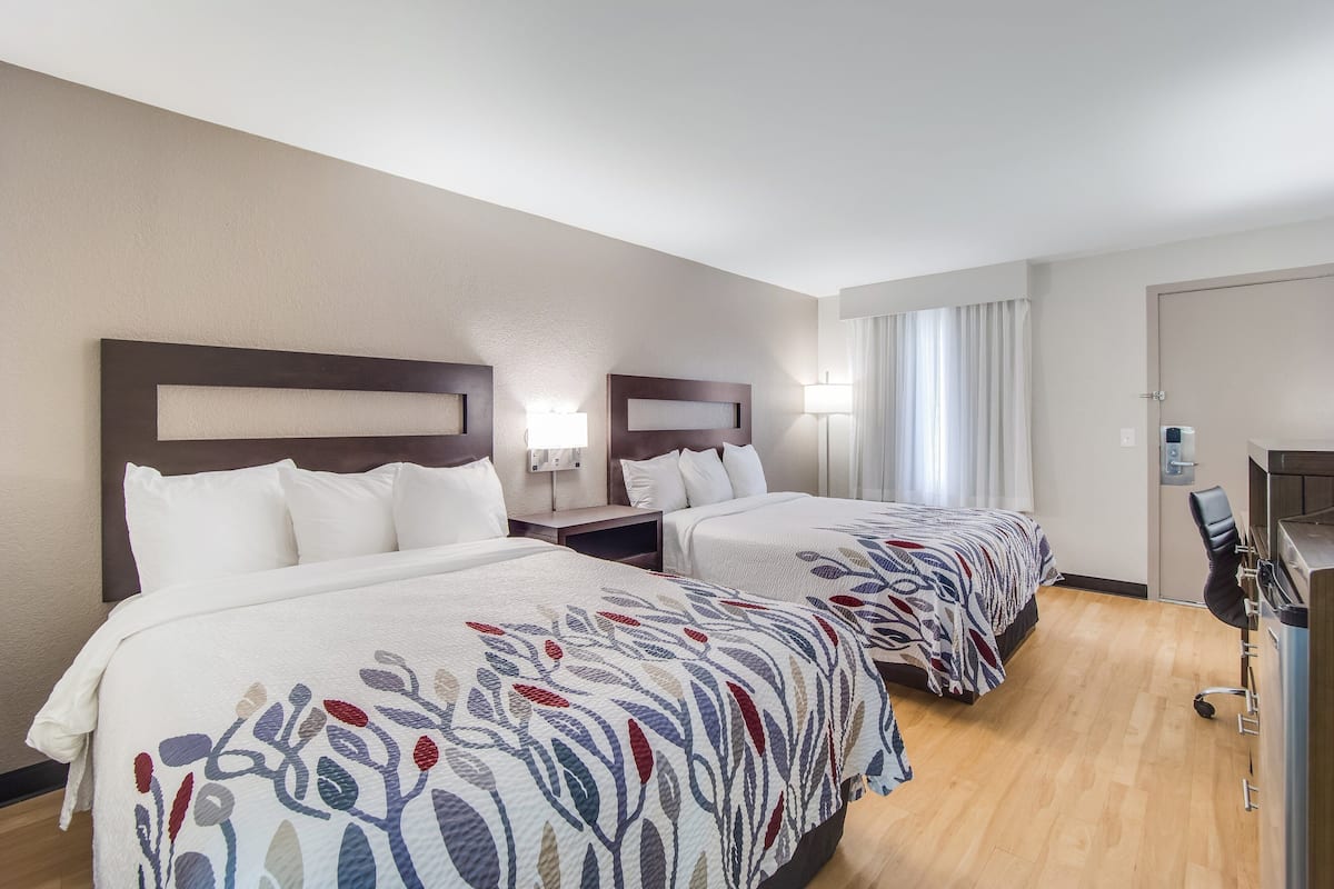 Une chambre d’hôtel avec deux lits, un bureau et une chaise.