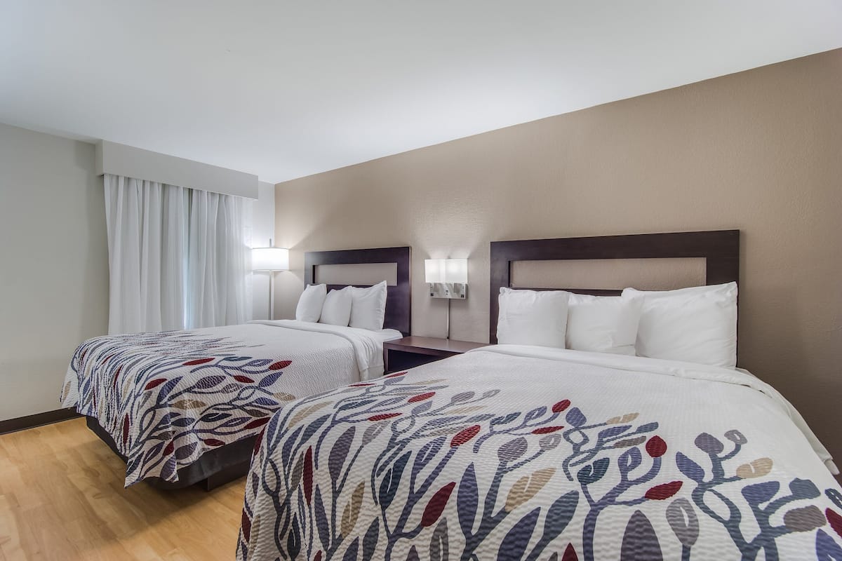 Une chambre d’hôtel avec deux lits, chacun recouvert d’une couvre-lit à motifs, dotée de lampes de chevet et décorée dans des tons neutres.