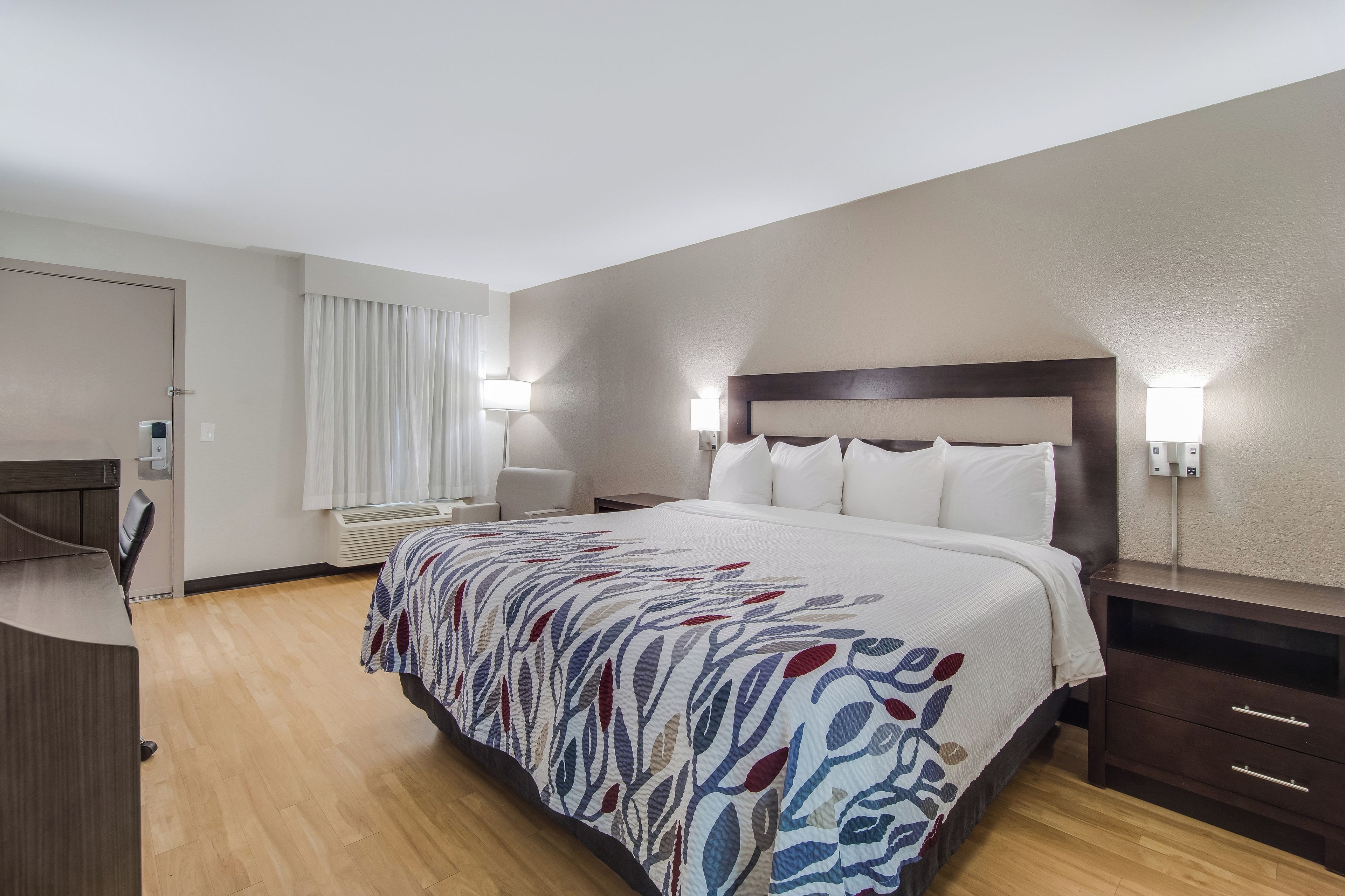 Een hotelkamer met een bed, nachtkastjes, een bureau en een stoel.