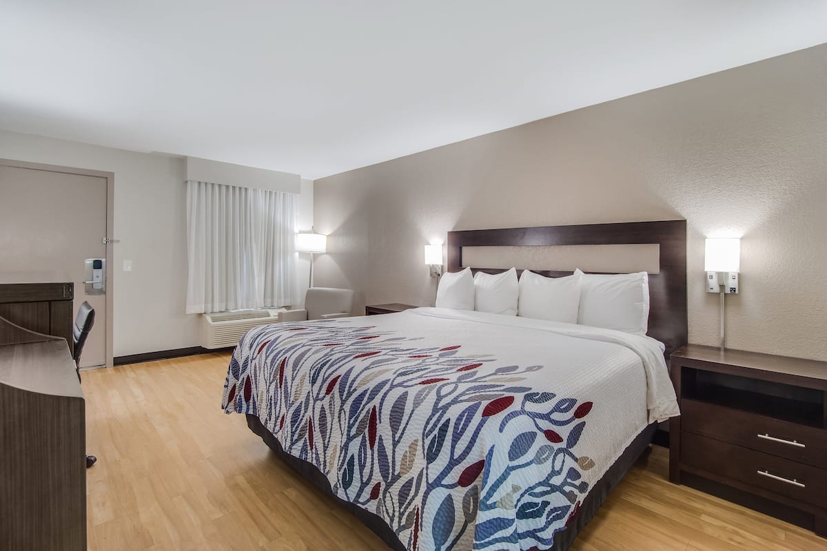 Ein Hotelzimmer mit einem großen Bett, Nachttischen, einem Schreibtisch und einem Sessel.