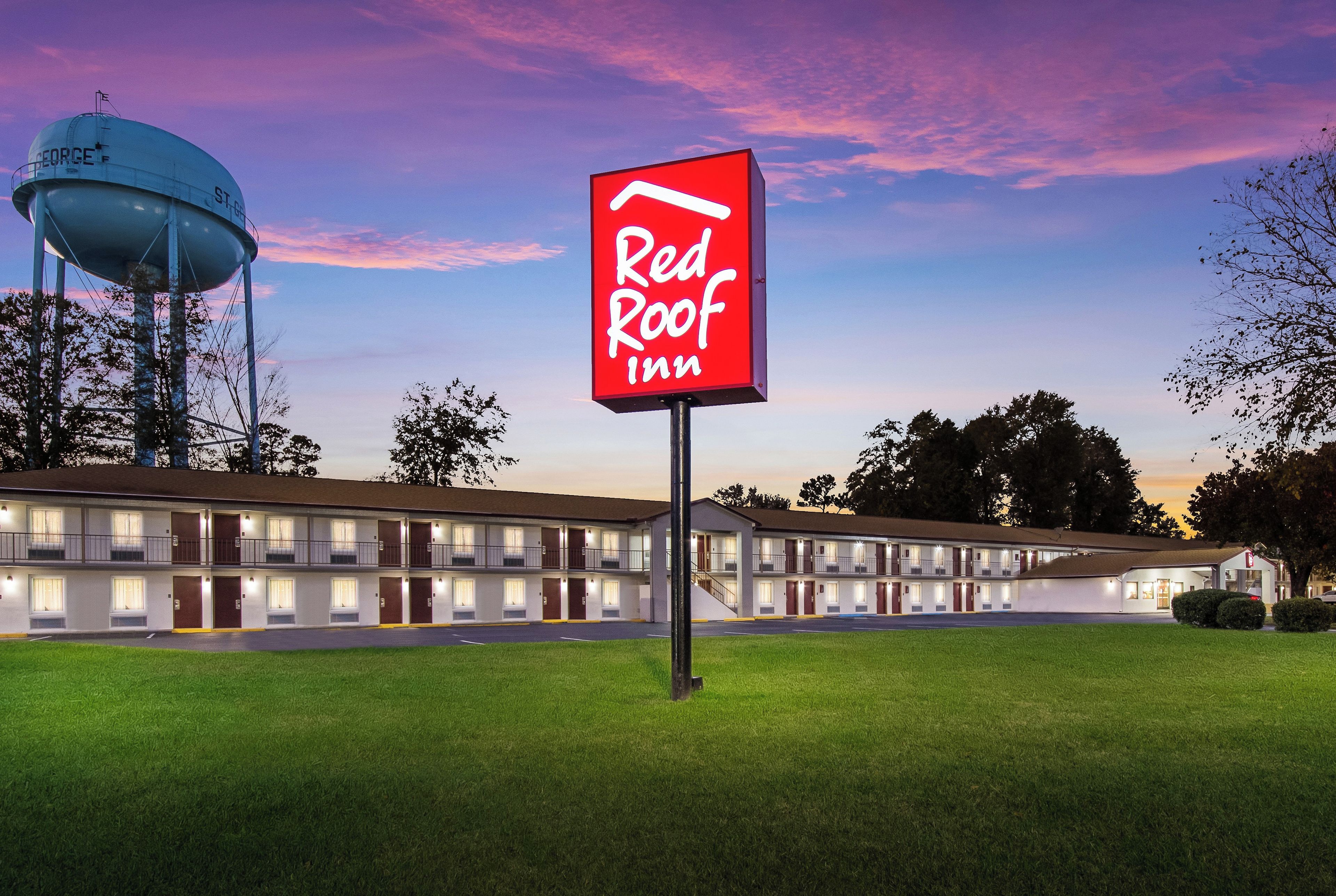 A Red Roof Inn with a large water tower in the background.