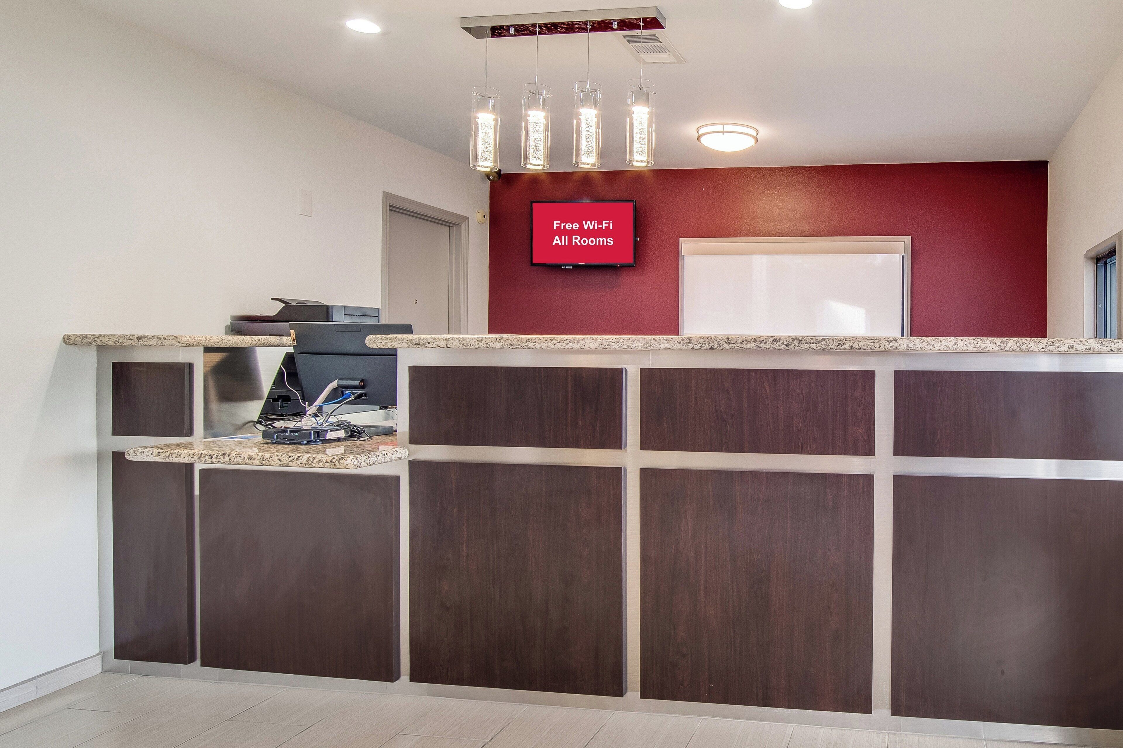 A reception area with a flat-screen TV displaying 'Free Wi-Fi All Rooms' and a counter with a coffee machine.