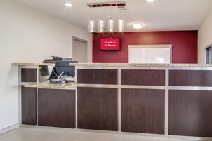 A reception area with a flat-screen TV displaying 'Free Wi-Fi All Rooms' and a counter with a coffee machine.