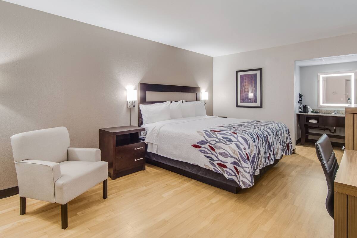 Une chambre d’hôtel avec un lit, une chaise, un bureau et une table de chevet.