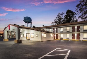 A motel with a water tower, multiple rooms, and a parking lot. - Red Roof Inn St George, SC (St. George)