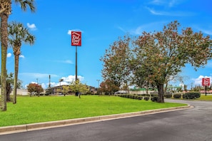 A Red Roof Inn with a clear sky, a well-maintained lawn, and a parking lot. - Red Roof Inn St George, SC (St. George)