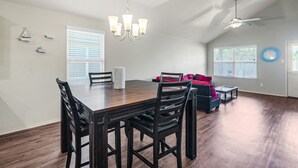 A dining area with a wooden table and chairs, a chandelier, and a ceiling fan.