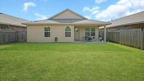 A two-story house with a covered patio and a fenced backyard.