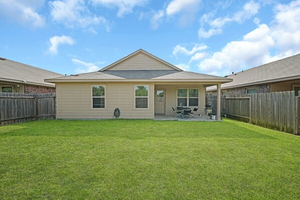 A two-story house with a covered patio and a fenced backyard.