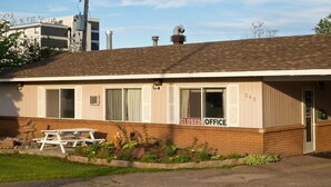 A single-story building with a closed office sign, a picnic table, and a brick facade.