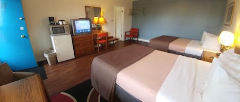 Ett hotellrum med två sängar, ett skrivbord med en dator, en mikrovågsugn och ett litet kylskåp.