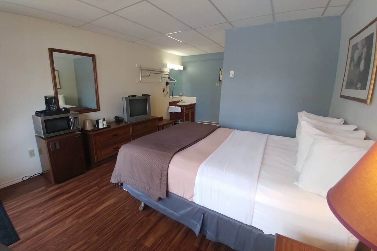 A hotel room with a bed, a desk with a computer, a television, and a bathroom.