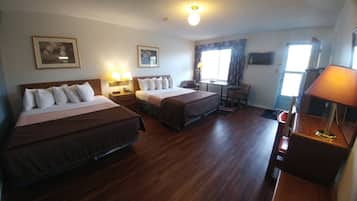 Une chambre d’hôtel avec deux lits, un bureau, une chaise, une lampe et une fenêtre avec des rideaux.