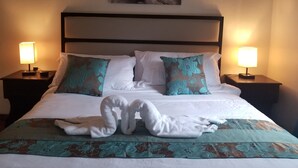 Een hotelkamer met een bed, twee bedlampen, een bloemenbedekking en een abstract schilderij aan de muur.