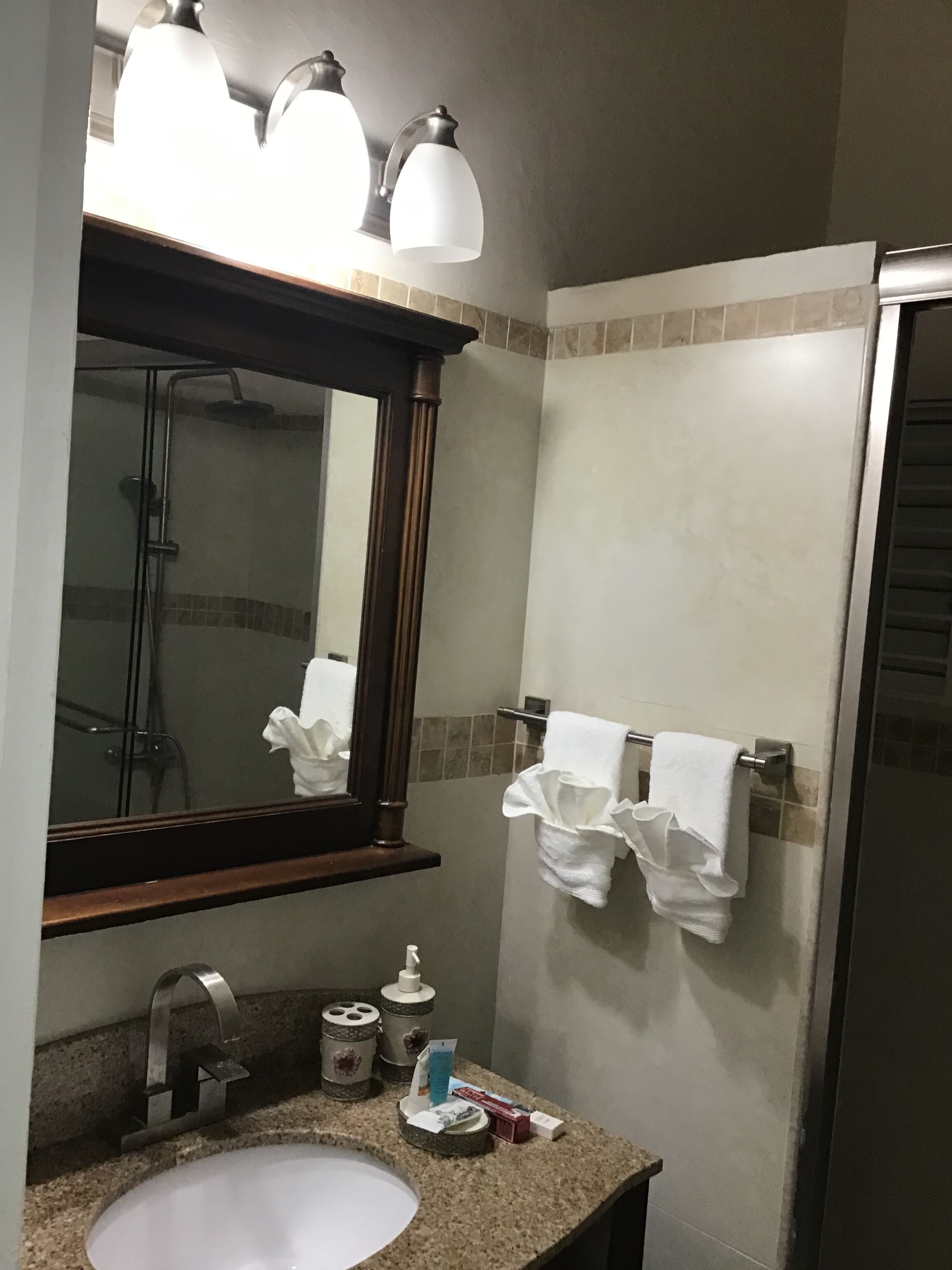 A bathroom with a sink, mirror, towel rack, and shower.