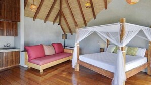 Ein Schlafzimmer mit Holzbalkendecke, einem Himmelbett und einer Couch mit Kissen.