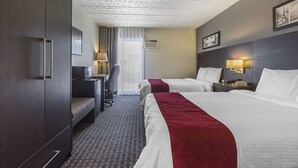 A hotel room with two beds, a desk, a chair, a wardrobe, and a window with curtains. - Hotel Le Principal (Granby)