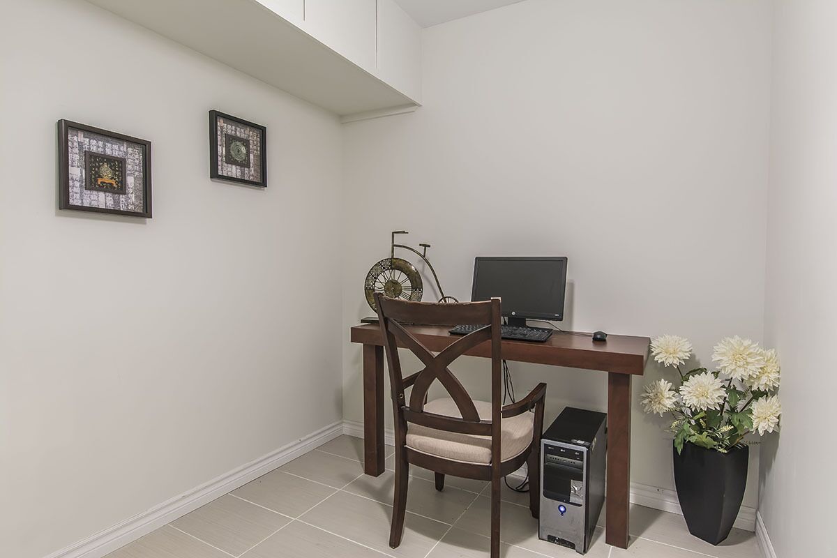 A small, neatly organized room with a wooden desk, a computer, a chair, and two framed pictures on the wall.