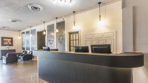 A reception area with a curved desk, multiple computer monitors, and a seating area with leather chairs. - Hotel Le Principal (Granby)