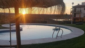 A swimming pool with a metal ladder and a thatched umbrella. - "Apartamento Amanecer "Vista al Campo, Golf, Piscinas, Playas - Cerca del Algarve (Ayamonte)