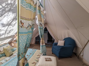 A cozy tent with a blue chair, a quilted bed, and a small table with a book. - BlueBird Nest 2.0, hot tub! Sibley double bell on huge deck!covered kitchen/bath (Hot Springs)