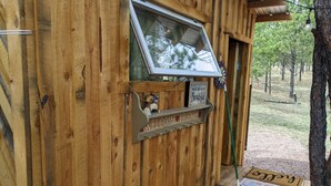 A wooden cabin with a welcome sign, a window, and a door leading to a porch. - BlueBird Nest 2.0, hot tub! Sibley double bell on huge deck!covered kitchen/bath (Hot Springs)