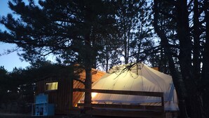 A tent with a wooden structure nearby, surrounded by trees. - BlueBird Nest 2.0, hot tub! Sibley double bell on huge deck!covered kitchen/bath (Hot Springs)