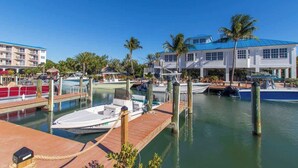 A marina with docked boats, a wooden dock, and a building with a blue roof.