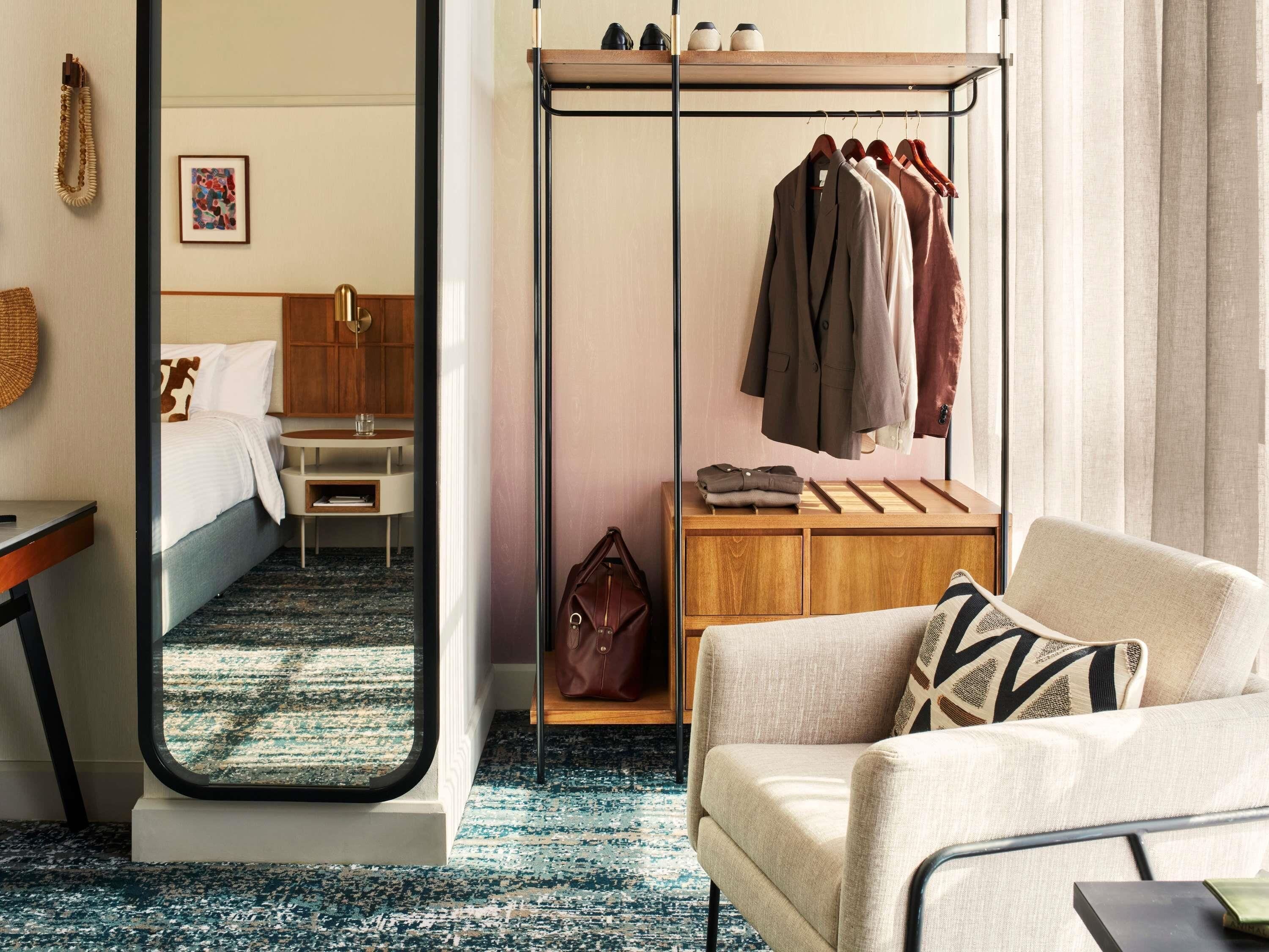 A hotel room with a bed, a desk, a mirror, a wardrobe, and a sofa.