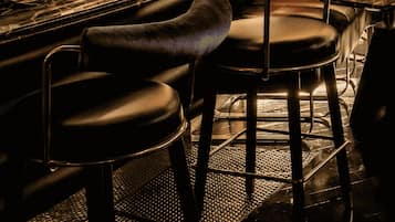 Una zona de bar con taburetes de cuero, una encimera de mármol y un mural en la pared.