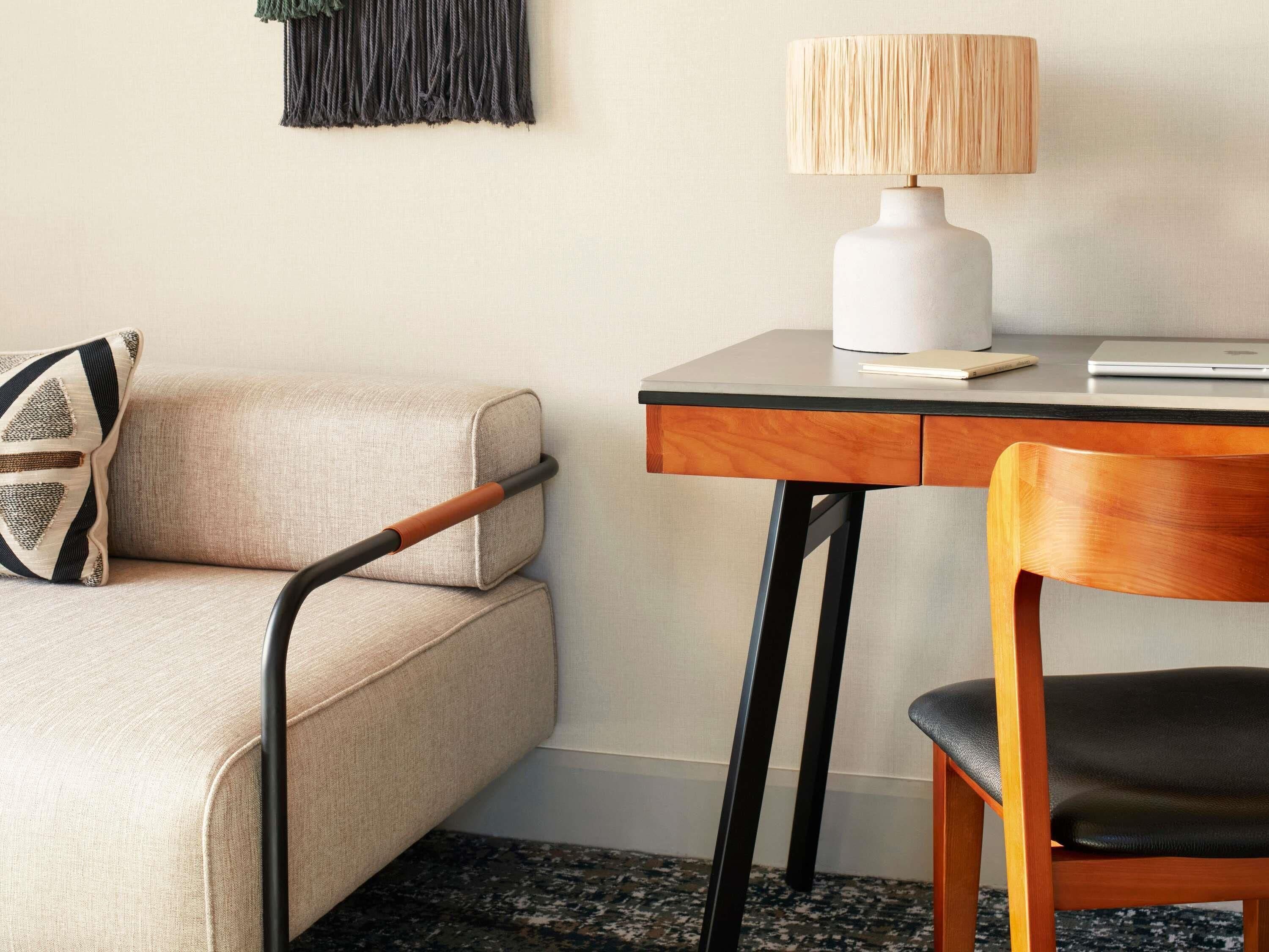 Una habitación moderna con sofá, escritorio con lámpara y una silla.