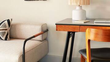 Una habitación moderna con sofá, escritorio con lámpara y una silla.
