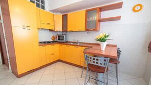 A kitchen with yellow cabinets, a wooden table, and a potted plant.