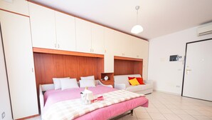 A bedroom with a bed, a sofa, a bedside table, and a wardrobe.