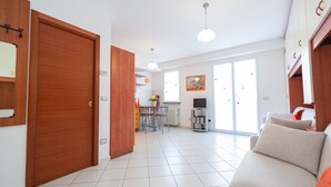 A spacious living area with a sofa, a dining table, and a kitchen in the background.
