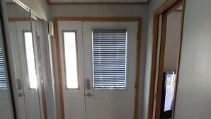 A spacious room with a large sliding glass door, a built-in bench with a cushion, and a window with blinds. - The Big Happy Place (Fergus)